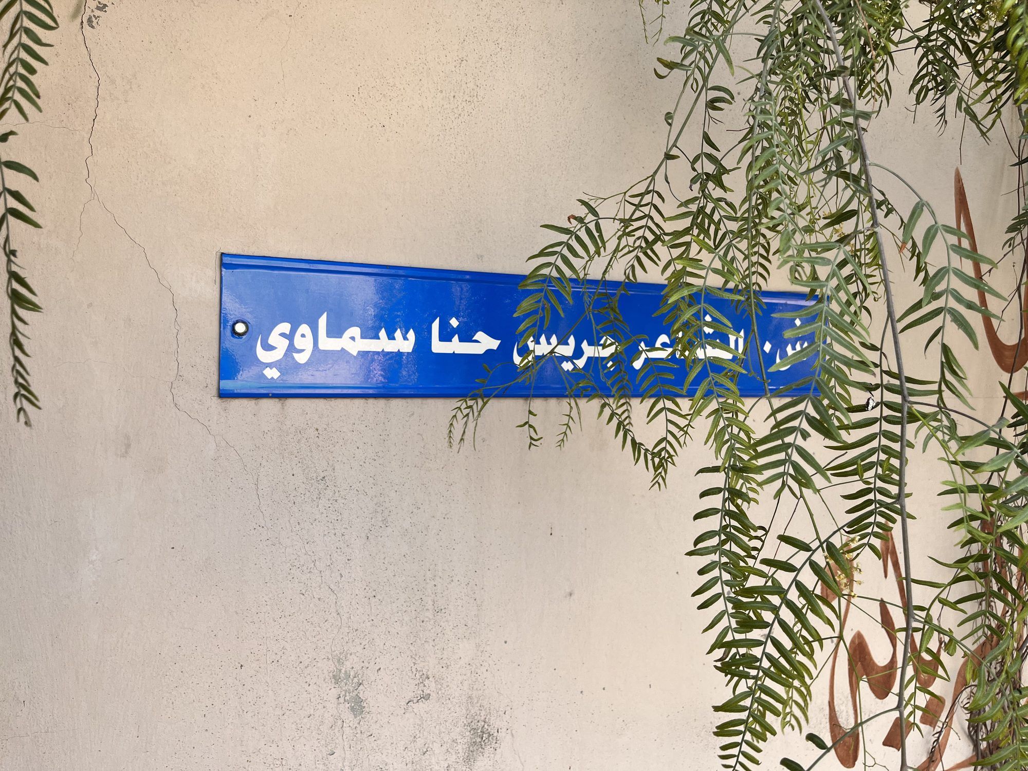 لافتة شارع الشاعر جريس حنا سماوي تحت أغصان متدلية